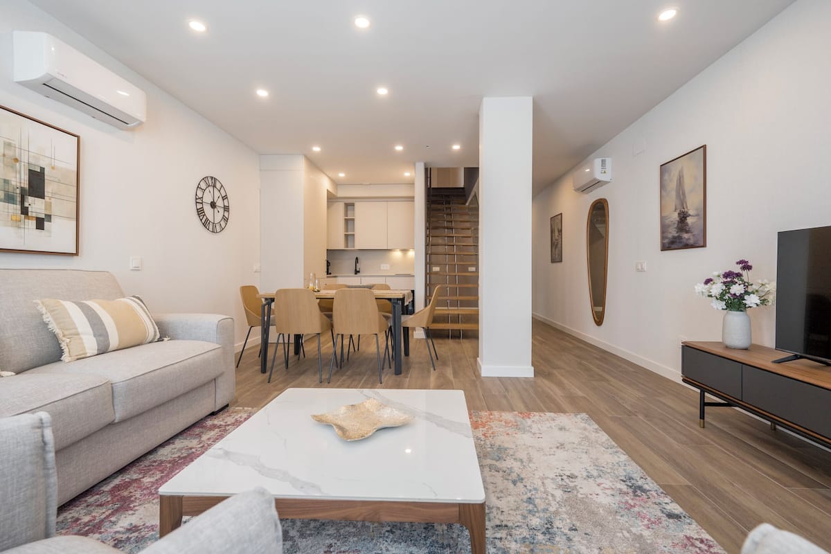 Una sala de estar moderna con un sofá, una mesa de centro y un mueble para televisión.