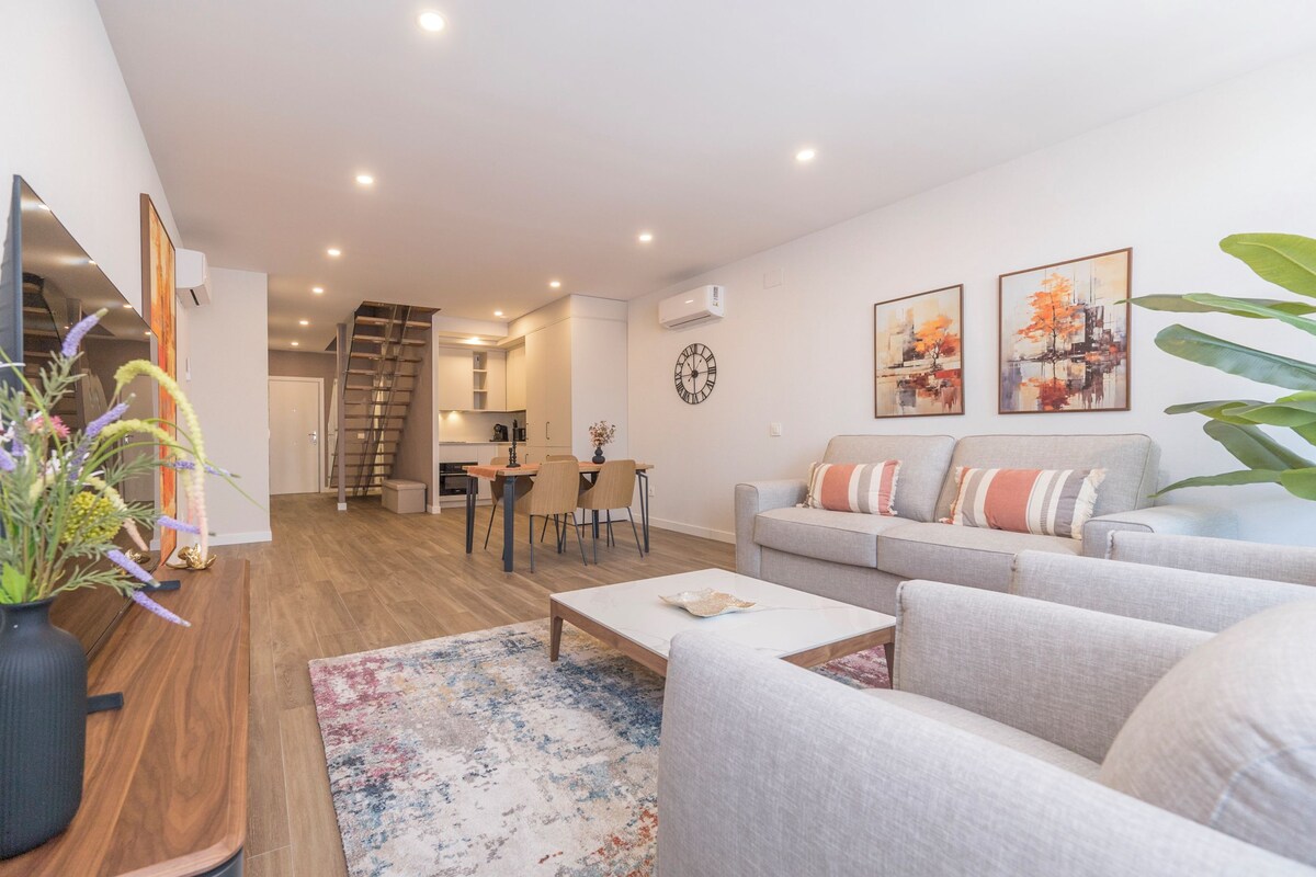 A modern living room with a sofa, coffee table, and a dining area with chairs and a table.