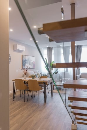 Una sala de estar moderna con comedor, piso de madera y una escalera.