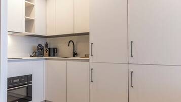A modern kitchen with white cabinets, a built-in oven, and a coffee maker on the countertop.