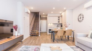 A modern living room with a sofa, coffee table, and a dining area with chairs and a table. - Apartamentos Dúplex Príncipe de Canalejas (Madrid)