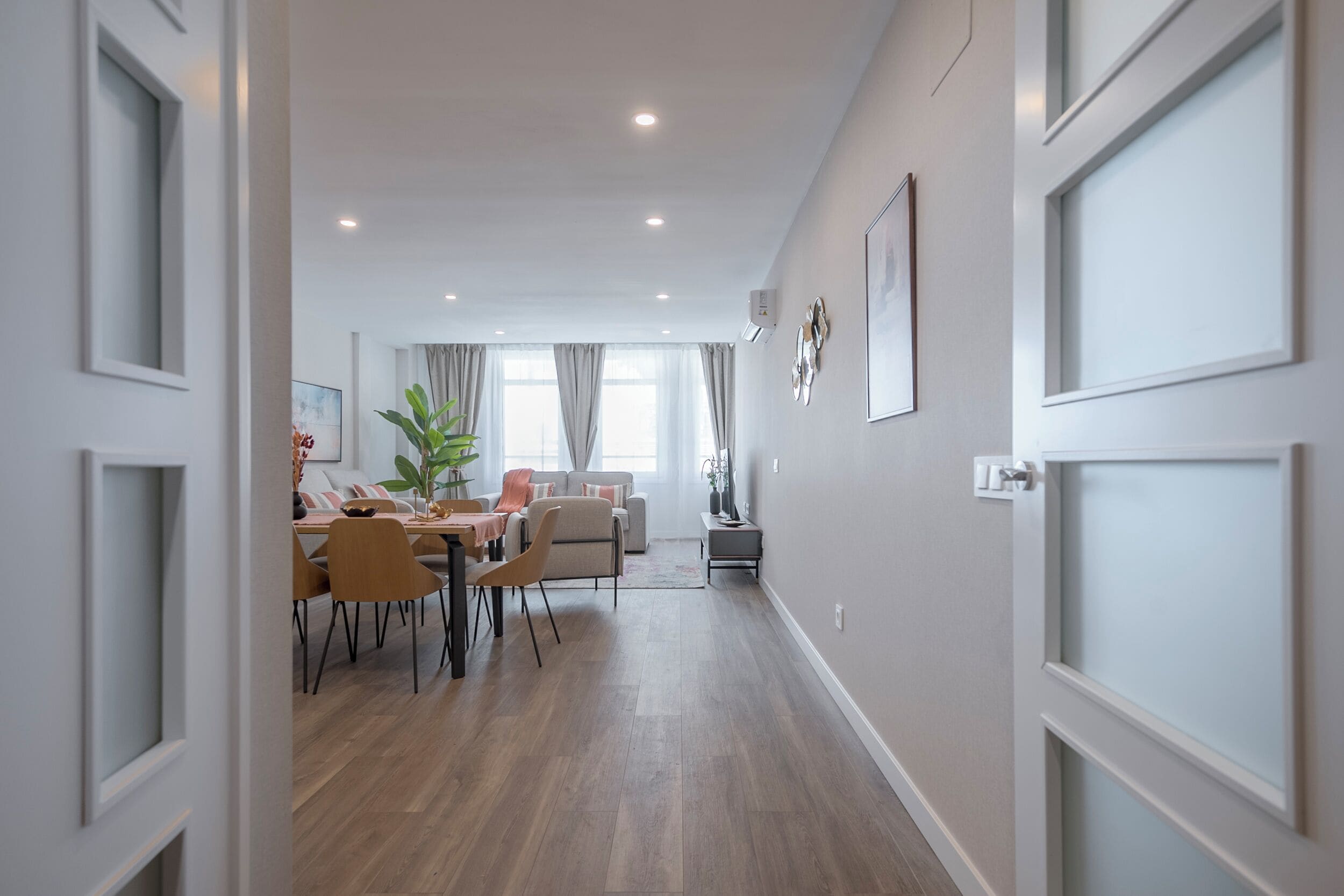 Un interior moderno con comedor, sofá y planta.
