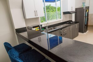 A modern kitchen with a black countertop, stainless steel appliances, and a window with a view of greenery. - Serene Seaside Retreat in Juan de Acosta - Private Pool & Comfort (Juan de Acosta)