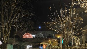 En stenmur med en skylt som lyder ”Djupgrottans hus” och en rustik byggnad med ett kupolformat tak.