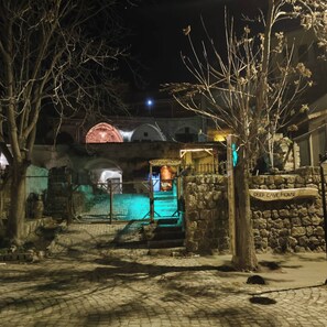 Un muro de piedra con un cartel que dice 'Deep Cave House' y un edificio rústico con techo abovedado.