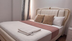 A neatly made bed with a white and pink bedspread, two leopard print pillows, and a folded white towel.