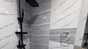 A bathroom with a shower, a sink, a towel ring, and a shelf with toiletries.