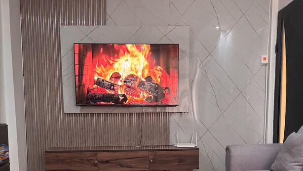 A modern living room with a fireplace, a flat-screen TV, and a round black coffee table.