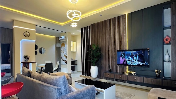 Una sala de estar moderna con un sofá gris, una mesa de centro y un televisor montado en la pared.