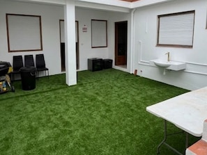 Habitació amb sòl de gespa artificial, un rentaplat i una taula.
