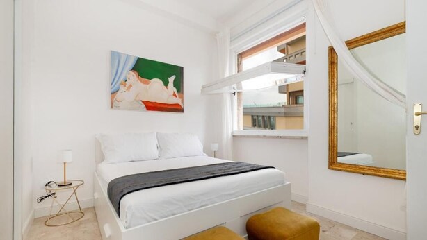 Una camera da letto con un letto, un quadro, una finestra e uno specchio.