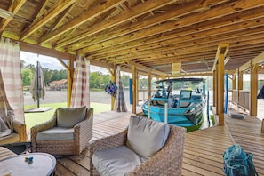 Un espacio al aire libre cubierto con muebles de mimbre, un barco amarrado fuera y una vista de un edificio al fondo.