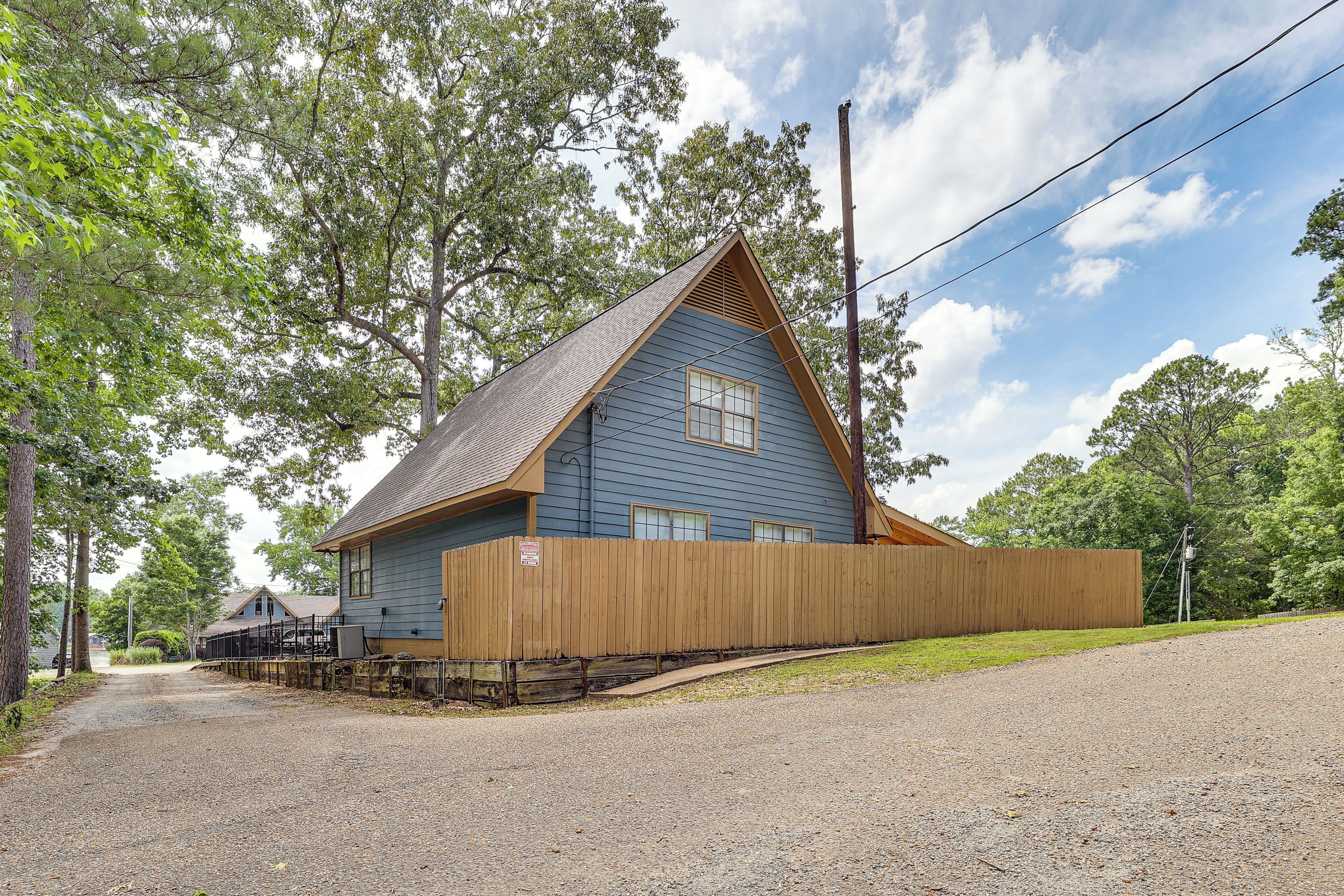 A blue building with a sloped roof, a wooden fence, and a gravel driveway.