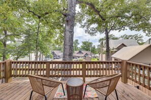 A wooden deck with wicker chairs and a table, overlooking a residential area with houses and parked cars. - Cozy Eclectic Cabin w/ Lake Views & Shared Dock! (Eclectic)