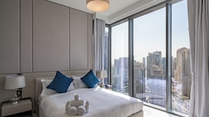 A modern hotel room with a large bed, two nightstands, a city view, and a large window. - Premium Skyline 1BR with Sea View LIV Marina (Dubai)