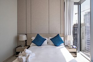 Et hotelværelse med en stor seng, to sengeborde, et vindue med udsigt til en bygning og et gardin.