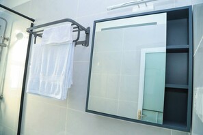 A bathroom with a glass shower enclosure, a towel rack with two towels, and a mirror with a door. - Cozy 2bed master-ensuite apt in Nairobi near the Airport and SGR train station (Nairobi)