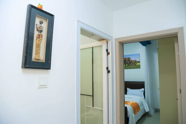 Ein Hotelzimmer mit einem Bett, einem gerahmten Bild an der Wand und einer Tür zu einem weiteren Raum.