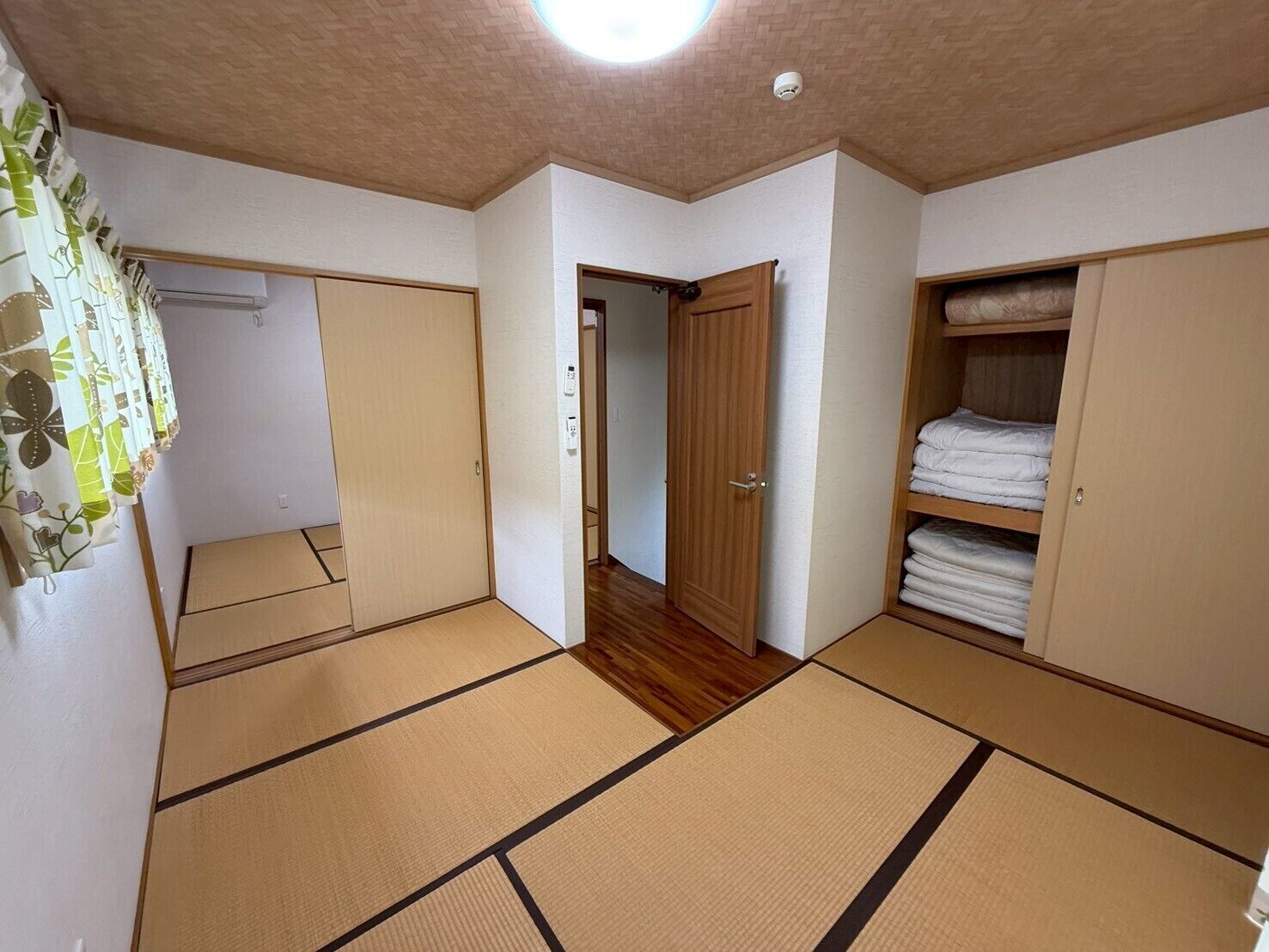 A room with tatami mats, a wardrobe, and a door leading to another room.