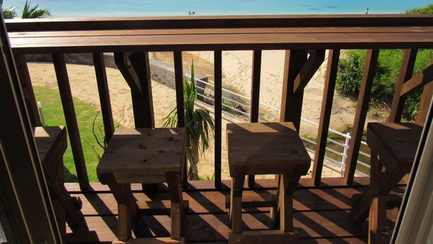 A wooden deck with two tables and a view of a beach and ocean. - Amami Lucky House (Amamishi,Kasaricho,OoagiKiseuttabaru)