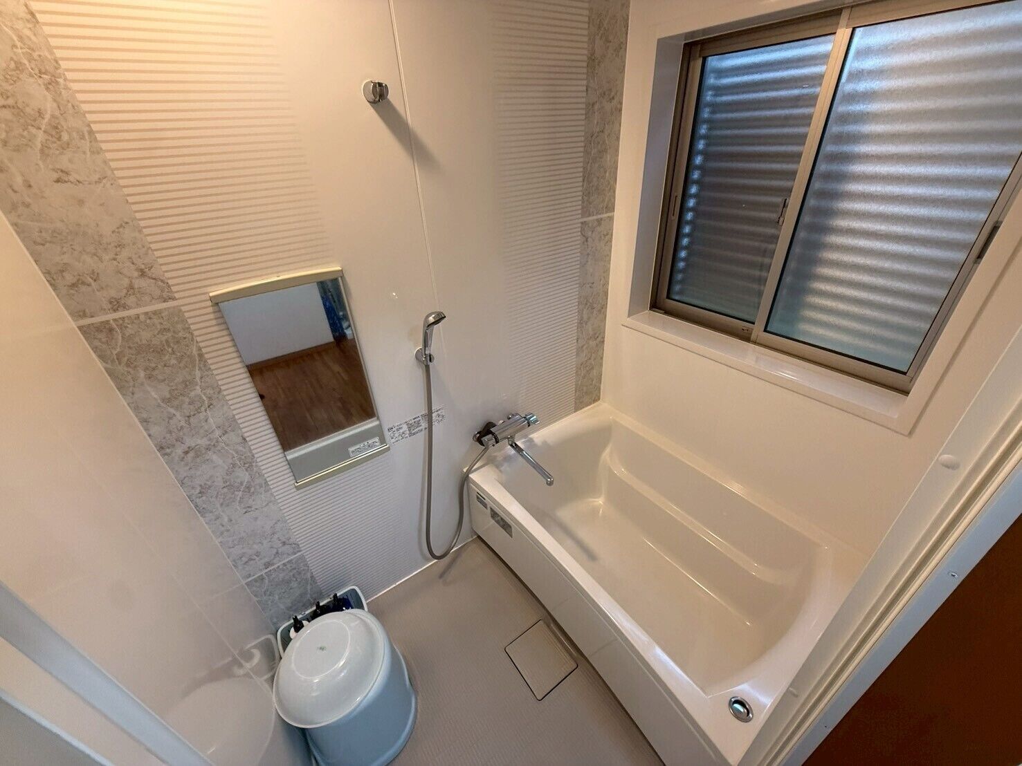 A bathroom with a bathtub, a shower, a toilet, and a window with blinds.