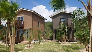 Two modern buildings with balconies, surrounded by well-maintained lawns and palm trees. - Amami Lucky House (Amamishi,Kasaricho,OoagiKiseuttabaru)