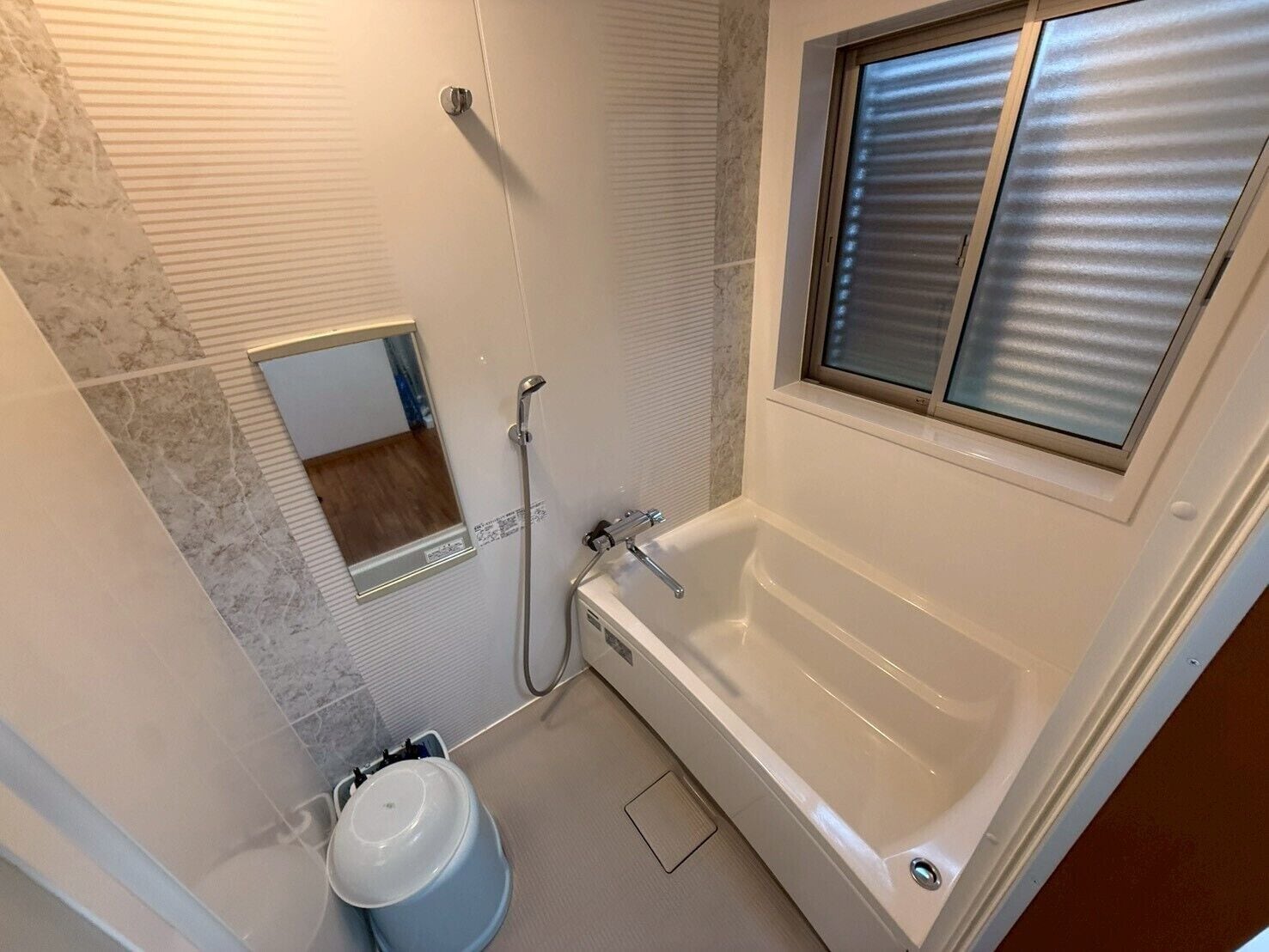 A bathroom with a bathtub, a shower, a toilet, and a window with blinds.