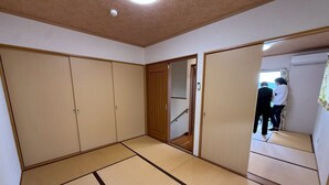 A room with tatami flooring, sliding doors, and a visible staircase leading to another area. - Amami Lucky House (Amamishi,Kasaricho,OoagiKiseuttabaru)