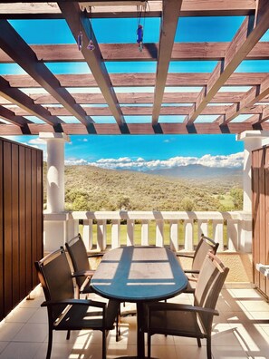 A covered patio with a table and chairs, a view of a mountainous landscape, and a wooden pergola structure. - Duplex in vacation village SEA (Saint-Raphaël)