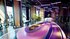 Een moderne sportschool met trainingsapparatuur, een gebogen zithoek en een plantenarrangement.