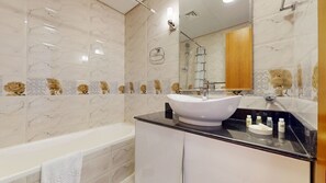 Een badkamer met een witte badkuip, een witte wastafel en een spiegel boven de wastafel.