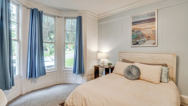Een slaapkamer met een groot bed, een nachtkastje met een lamp en een schilderij aan de muur.