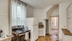 Een keuken met een fornuis, oven, magnetron, koelkast en een raam met gordijnen.