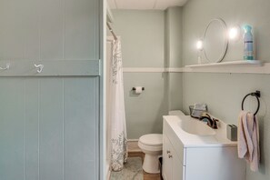 Een badkamer met toilet, wastafel, spiegel en douchegordijn.