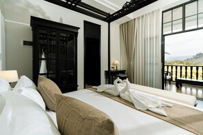 Une chambre d’hôtel avec un lit, une armoire, un bureau avec une lampe et un balcon avec vue.