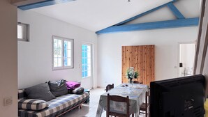 Une pièce comprenant un canapé, une table à manger avec des chaises, un buffet en bois et un plafond avec des poutres bleues.