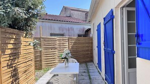 Une terrasse avec une table et des chaises, une clôture en bois et une porte bleue.