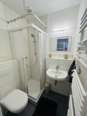 Ein modernes Badezimmer mit Dusche, Toilette, Waschbecken und einem Spiegel darüber.