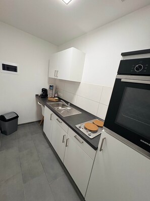 Eine moderne Küche mit weißen Schränken, einem schwarzen Backofen und einer Kaffeemaschine.