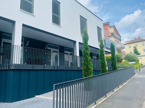 Een modern gebouw met balkon, een metalen hek en uitzicht op de straat.