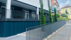 A modern building with a balcony, a metal fence, and a street view. - Sanssouci Holiday Apartment 13 (Bad Kissingen)