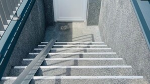 A stairway leading to a door with two signs, metal railings, and a concrete wall. - Sanssouci Holiday Apartment 13 (Bad Kissingen)