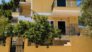 Un edificio de varios pisos con balcones, una escalera y un árbol en primer plano.