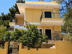 Un edificio de varios pisos con balcones, una escalera y un árbol en primer plano.