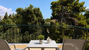 Un balcón con una mesa, dos sillas, una planta en maceta y una taza.