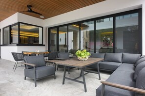 An outdoor patio with a wooden table, grey sofas, and chairs. - Luxury Villa w/ Pier and Beach, Resort Amenities (Cozumel)