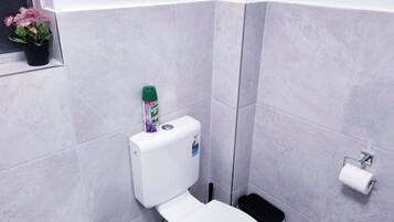Une salle de bain équipée de toilettes, d’un bidet et d’une petite poubelle.