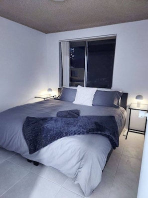 Une chambre à coucher avec un grand lit, une fenêtre et deux tables de chevet.