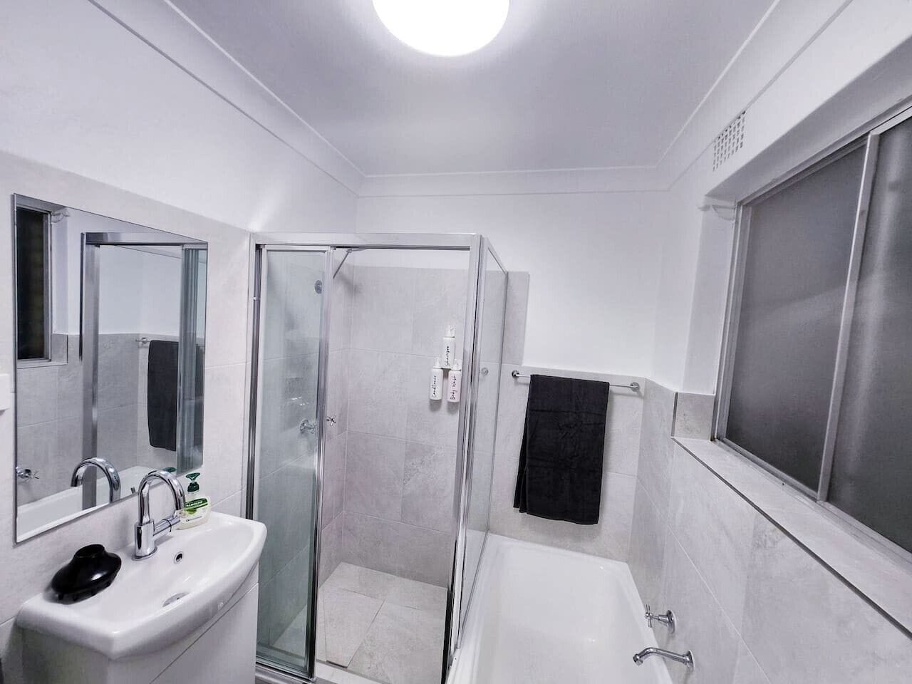Une salle de bain moderne avec une douche à parois de verre, un lavabo blanc et une baignoire.
