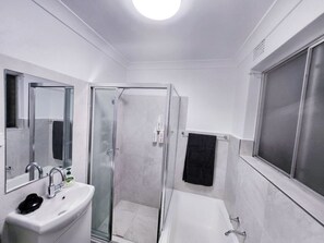 Une salle de bain moderne avec une douche à parois de verre, un lavabo blanc et une baignoire.